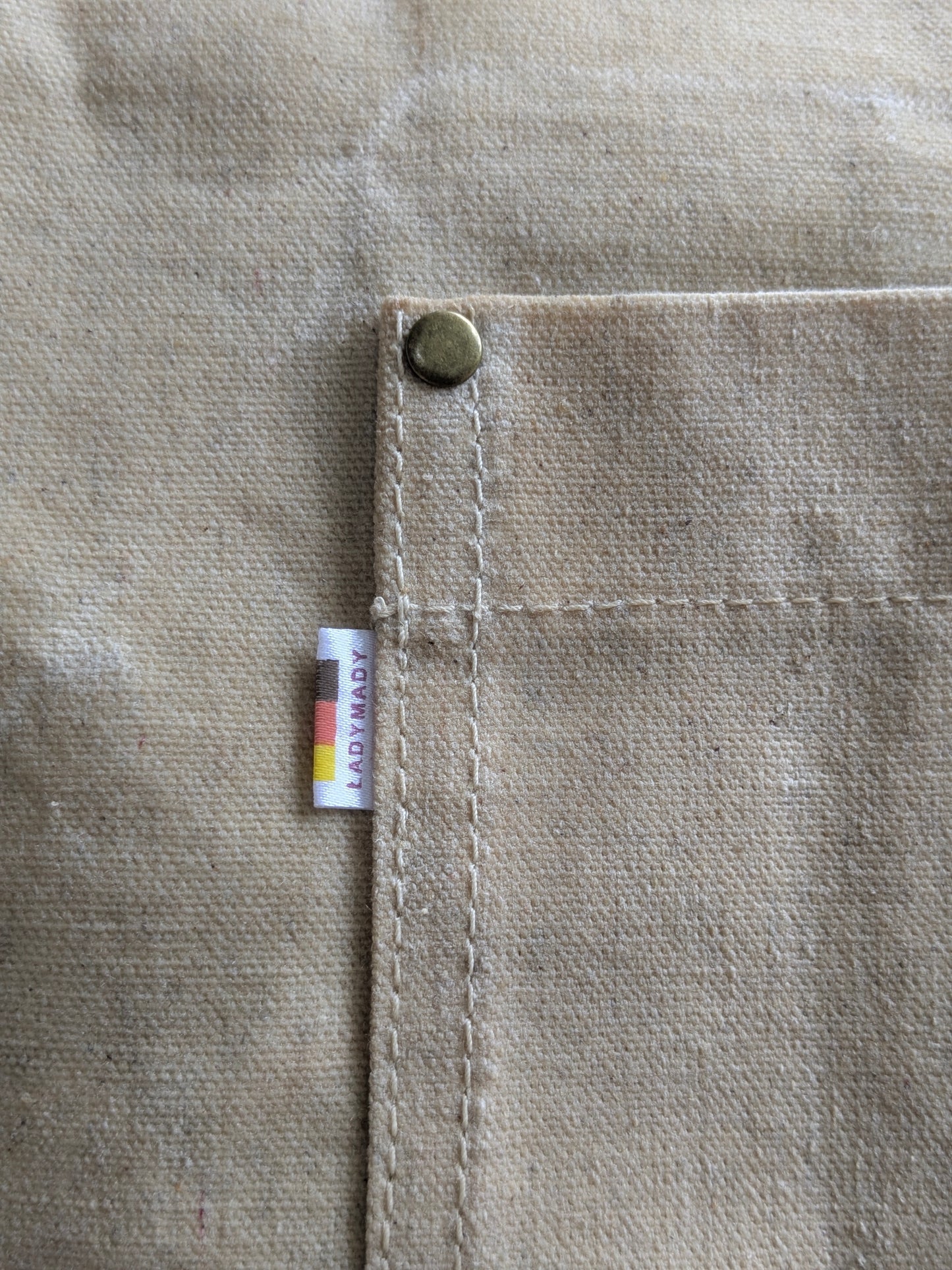 Close-up of LadyMady Handmade Waxed Canvas Tote Bag showcasing the durable stitching and brass button on the pocket. Waxed canvas tote bag.